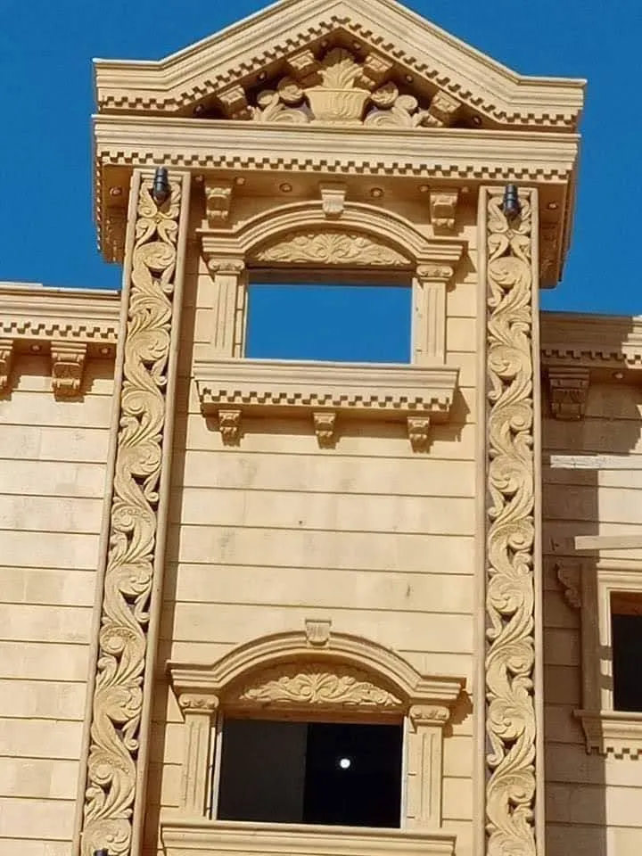 واجهة عمارة من الحجر الهاشمي بتاج مثلث وشريطين زخرفيين